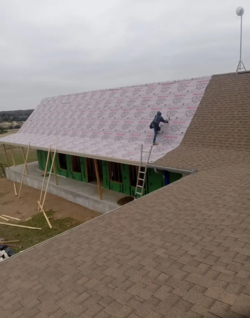 Worker preparing underlayment for a metal roof installation in Taylors